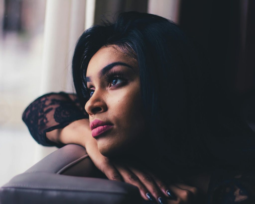 Une femme pensive regarde par la fenêtre, incarnant la tranquillité et l'introspection.