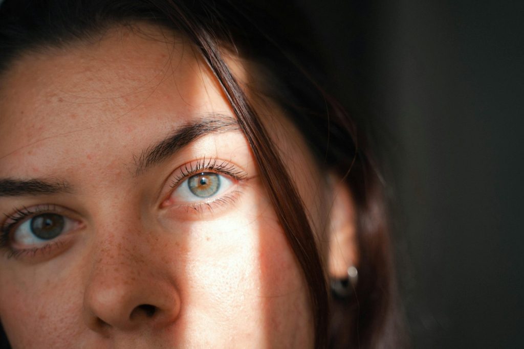 Gros plan intime du visage d'une femme, baigné d'une douce lumière naturelle qui met en valeur ses traits.