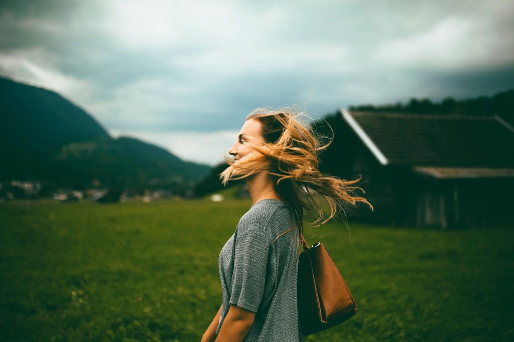 Une femme se tient debout dans un champ verdoyant, savourant la liberté et l'air frais d'un paysage rural.