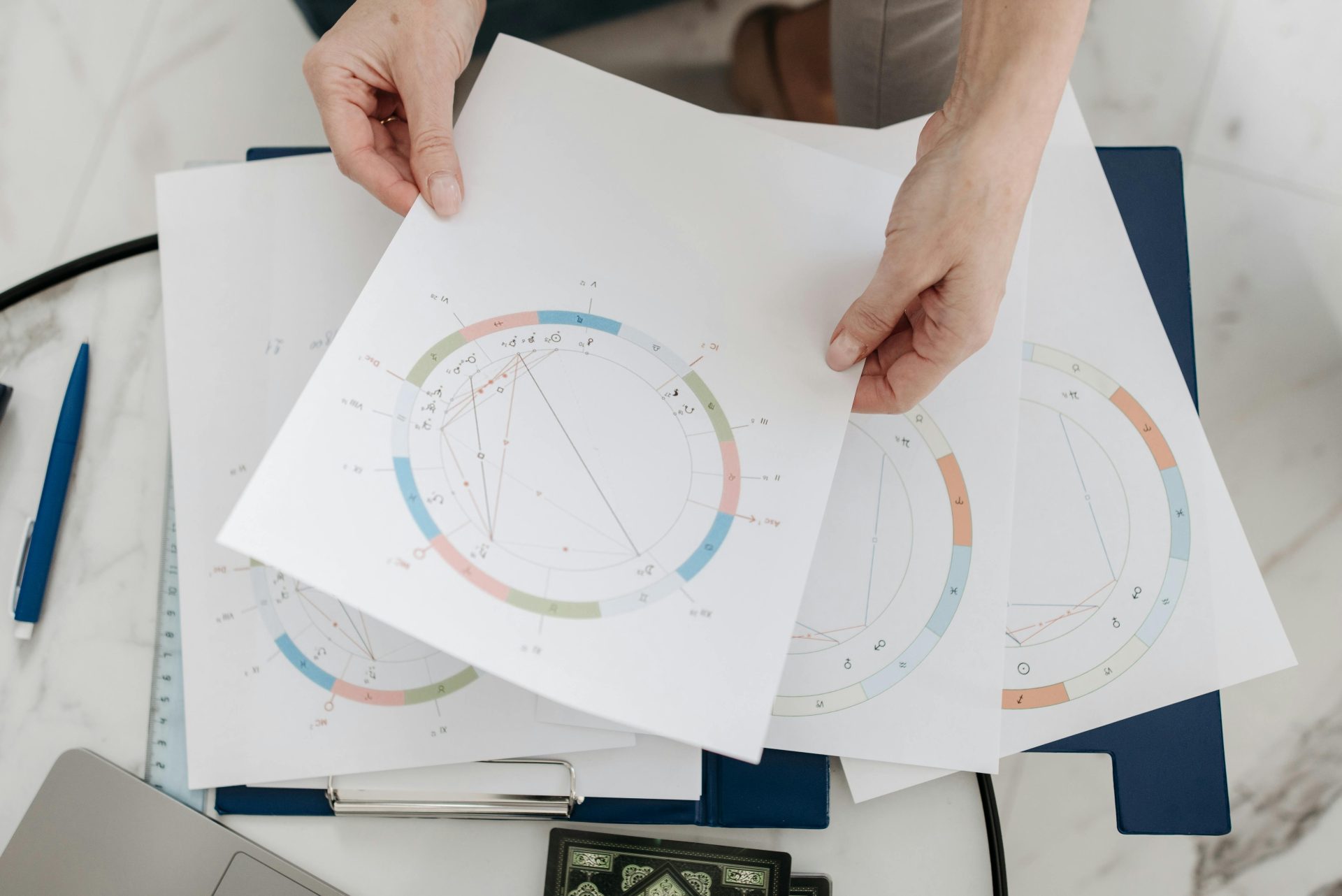 Des mains tenant des cartes et des graphiques astrologiques, symbolisant les horoscopes et la divination.