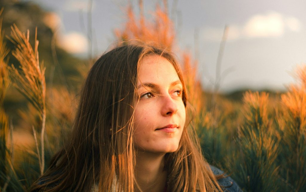 Jeune femme regardant au loin dans un champ de hautes herbes