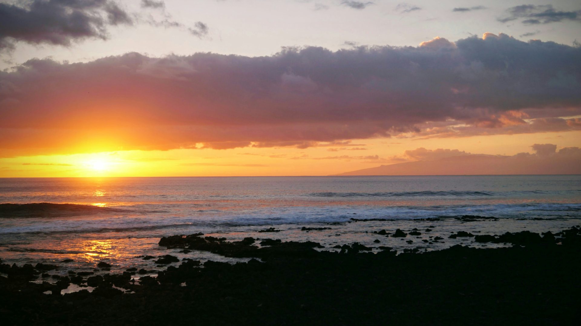 Le soleil se couche sur l'océan par une journée nuageuse.