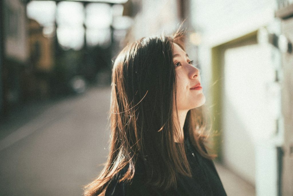 Jeune femme regardant vers le ciel, les cheveux au vent